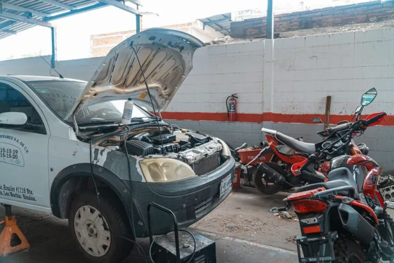 Ce verifici la o mașină second-hand înainte de cumpărare Mecanic care inspectează suspensia unei mașini ridicate pe elevator într-un service auto